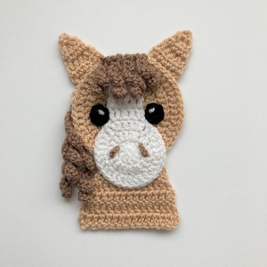 May include: A crocheted horse head applique in brown and white. The horse has a brown mane and tail, and black eyes.