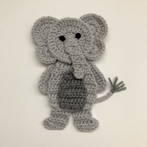 Puede incluir: Un juguete de elefante de crochet gris con ojos negros y una cola gris.