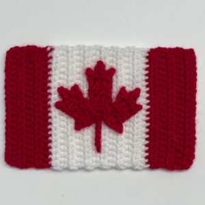 May include: A crocheted Canadian flag design. The flag features a red maple leaf on a white background, with red borders. The item is rectangular in shape and made with red and white yarn.