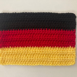 Könnte beinhalten: Eine gehäkelte deutsche Flagge mit schwarzen, roten und gelben Streifen.
