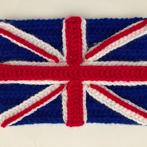 Può includere: Una bandiera Union Jack all'uncinetto realizzata con filato rosso, bianco e blu. La bandiera è realizzata con un semplice motivo a punto e ha una superficie leggermente testurizzata.