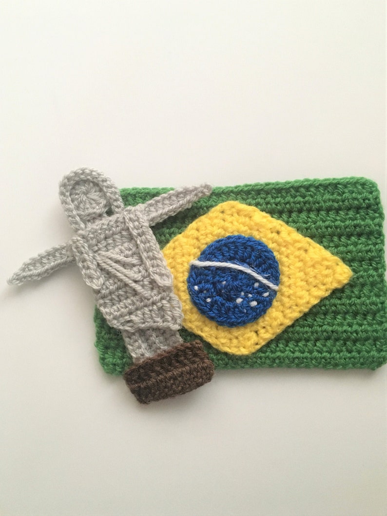 Może przedstawiać: Haftowany obraz Chrystusa Odkupiciela w Rio de Janeiro w Brazylii, stojący obok haftowanej brazylijskiej flagi.