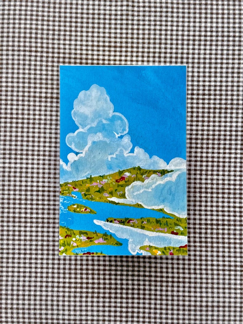 May include: A rectangular painting depicts a landscape with a bright blue sky and fluffy white clouds. Below, a green and yellow landscape is bisected by a blue river. The artwork is on a white background.