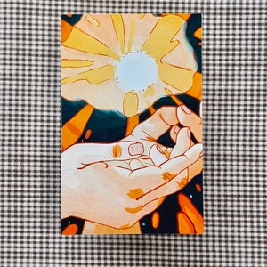 May include: A rectangular art print featuring a stylized illustration of two hands reaching towards a large, yellow flower with a light blue center. The background is dark blue with orange accents. The artwork is on a checkered surface.