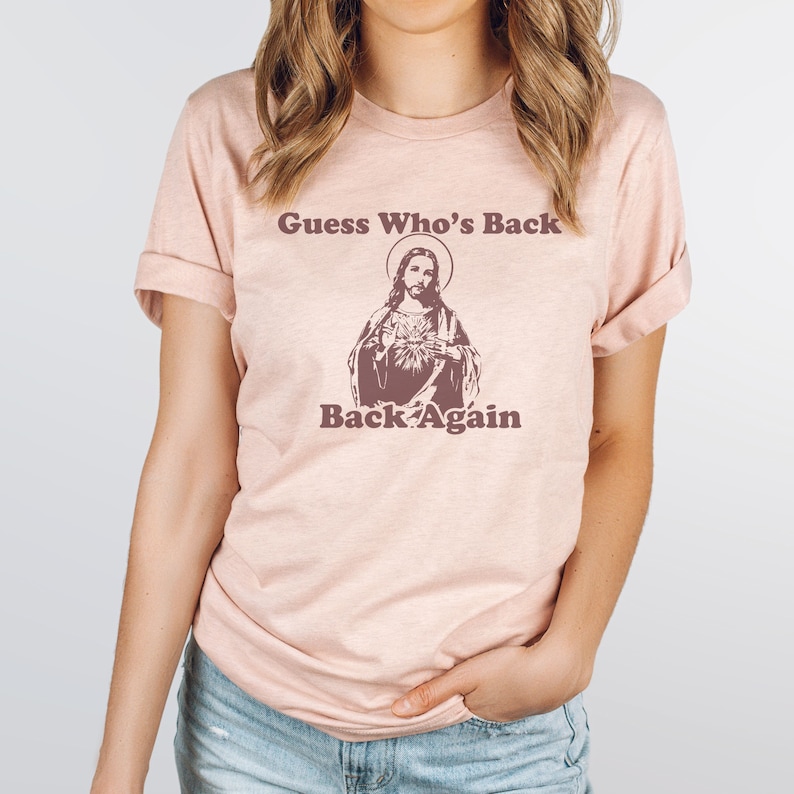 May include: A pink t-shirt with a graphic of Jesus and the text "Guess Who's Back Back Again".