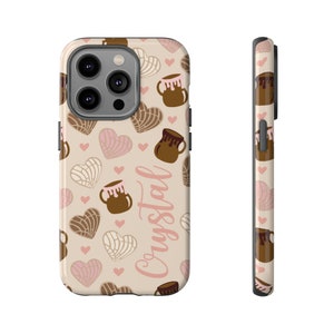 May include: A phone case with a repeating pattern of brown mugs, heart-shaped pastries, and pink hearts on a beige background. The name "Crystal" is written in pink script. The side of the case is also visible.