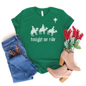 May include: Green t-shirt with a white graphic of three wise men riding camels and a star above them. The text "tonight we ride" is printed below the image.