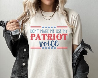 May include: A beige t-shirt with a red, white, and blue graphic that says "Don't make me use my PATRIOT voice".