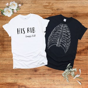 May include: Two t-shirts, one white and one black. The white t-shirt has the text "HIS RIB Genesis 2:22" printed on it. The black t-shirt has a graphic of a ribcage printed on it.
