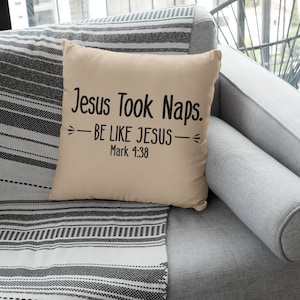 May include: Beige throw pillow with black text that reads "Jesus Took Naps. -BE LIKE JESUS- Mark 1:38" on a gray couch with a black and white striped throw blanket.