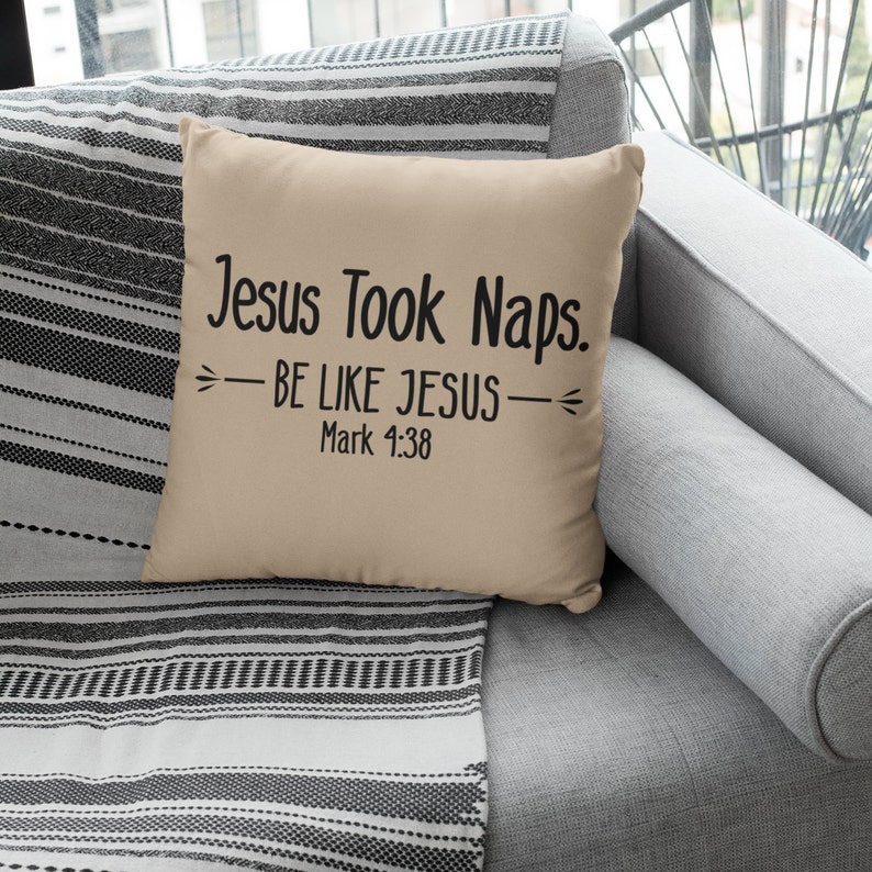 Puede incluir: Coj&iacute;n beige con texto negro que dice "Jesus Took Naps. -BE LIKE JESUS- Mark 1:38" en un sof&aacute; gris con una manta de rayas blancas y negras.