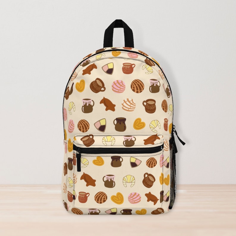 May include: A beige backpack with a colorful pattern of Mexican pastries and hot chocolate. The pattern includes conchas, pan dulce, churros, and traditional clay mugs.