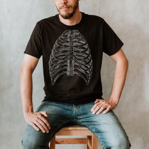 May include: A black t-shirt with a white anatomical illustration of a rib cage.