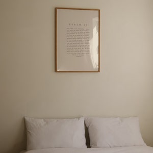 May include: A white bed with two white pillows and a framed print on the wall behind it. The print is a light beige color and has the text "PSALM 23" in black lettering.