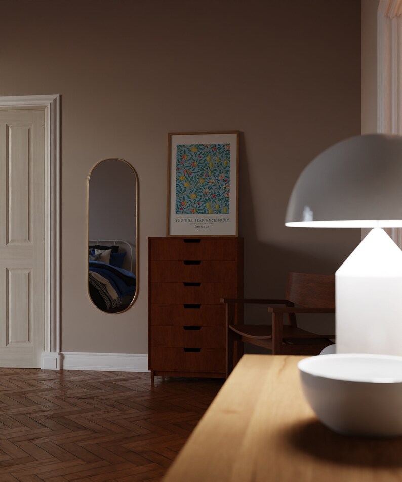 May include: A wooden dresser with six drawers, a white lamp with a white shade, a chair, and a framed print with a floral design and the text "You will bear much fruit" John 15:2. The dresser is in a room with a wooden floor and a white door.