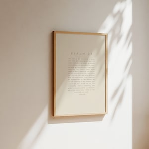 May include: A framed print of Psalm 23 in a light beige color with a wooden frame. The text is in black and reads "The Lord is my shepherd, I shall not want. He makes me lie down in green pastures; He leads me beside quiet waters. He restores my soul. He leads me in paths of righteousness for His name's sake. Even though I walk through the valley of the shadow of death, I will fear no evil, for You are with me; Your rod and Your staff, they comfort me. You prepare a table before me in the presence of my enemies; You anoint my head with oil; my cup overflows. Surely goodness and mercy shall follow me all the days of my life, and I will dwell in the house of the Lord forever."
