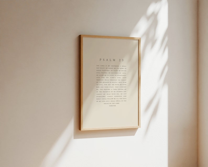 May include: A framed print of Psalm 23 in a light beige color with a wooden frame. The text is in black and reads "The Lord is my shepherd, I shall not want. He makes me lie down in green pastures; He leads me beside quiet waters. He restores my soul. He leads me in paths of righteousness for His name's sake. Even though I walk through the valley of the shadow of death, I will fear no evil, for You are with me; Your rod and Your staff, they comfort me. You prepare a table before me in the presence of my enemies; You anoint my head with oil; my cup overflows. Surely goodness and mercy shall follow me all the days of my life, and I will dwell in the house of the Lord forever."