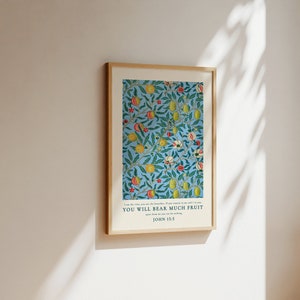 May include: A framed print with a blue background and a repeating pattern of green leaves, yellow lemons, and red and white flowers. The text "YOU WILL BEAR MUCH FRUIT" is printed below the image, with "JOHN 15:5" printed below the text.