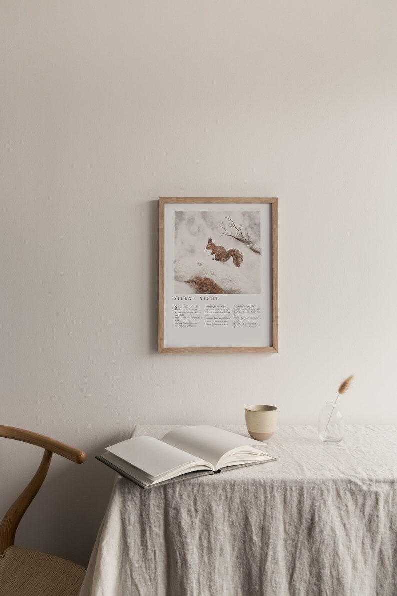May include: A framed print with a watercolor illustration of a squirrel in a snowy forest. The print includes the lyrics to the Christmas carol "Silent Night".
