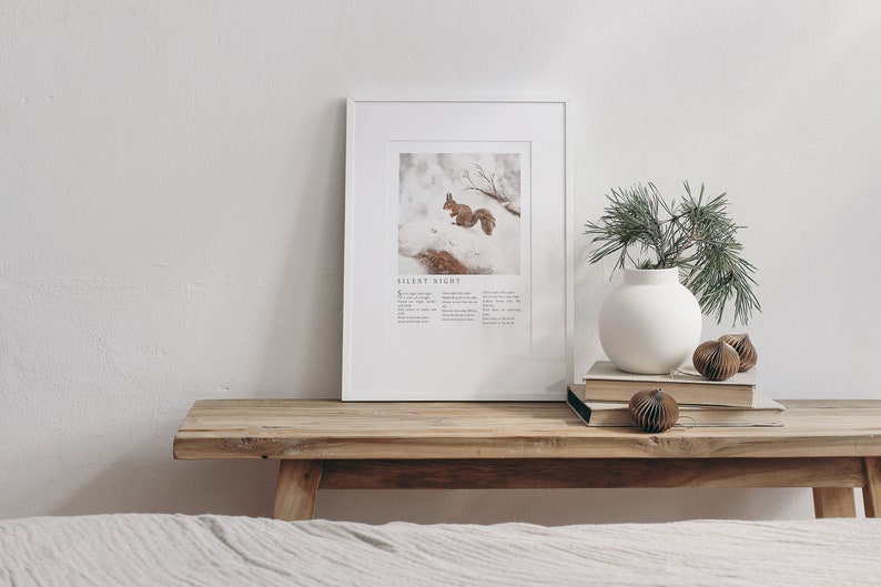 May include: A framed print with a white background and a picture of a squirrel in the snow. The print has the text "Silent Night" and the lyrics to the song printed below the image.