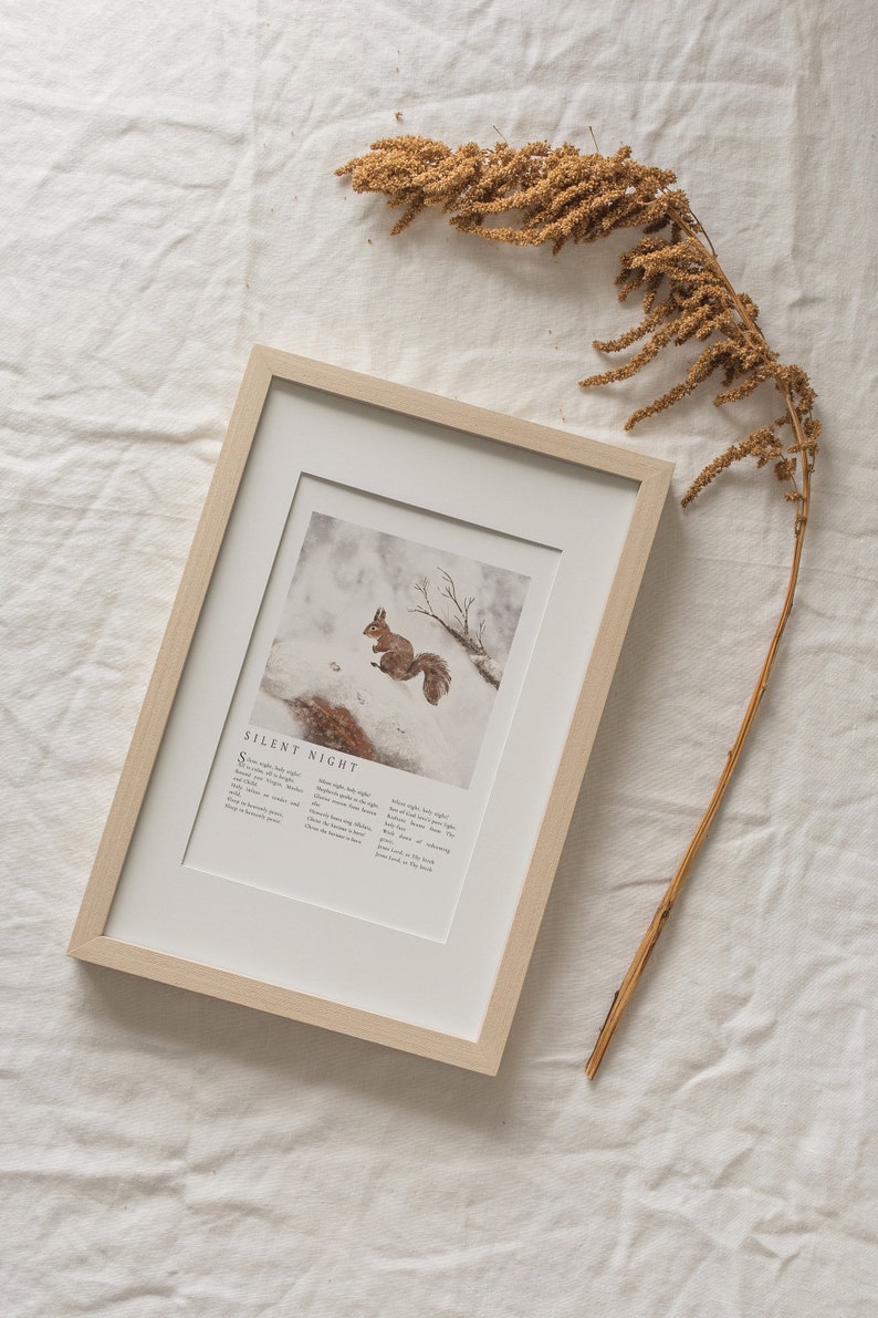 May include: A framed print with a watercolor illustration of a squirrel in a snowy forest. The print includes the lyrics to the Christmas carol "Silent Night".