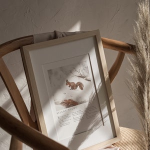 May include: A framed print with a watercolor illustration of a squirrel in a snowy forest. The print includes the lyrics to the Christmas carol "Silent Night".