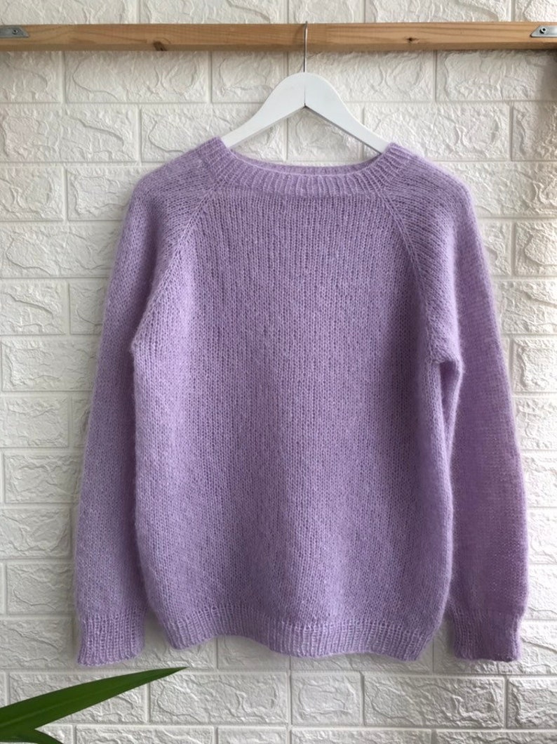 May include: A soft, light purple sweater with long sleeves and a round neckline.