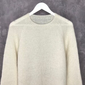 May include: A white, fluffy knit sweater with a round neckline and long sleeves.