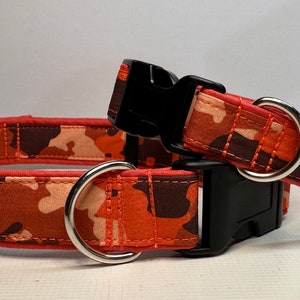 May include: Two orange and brown camouflage dog collars with black buckles and silver D-rings.