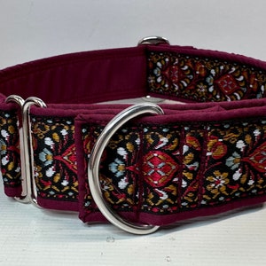 May include: A maroon dog collar with a silver buckle and a patterned fabric design featuring red, gold, white and blue colours.