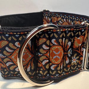 May include: A black and orange floral patterned dog collar with a silver buckle.