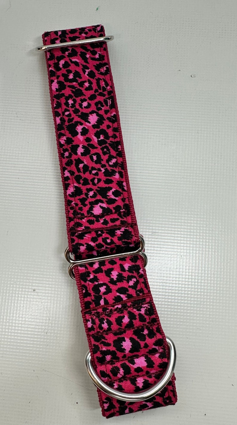 May include: A pink and black leopard print dog collar with silver hardware.