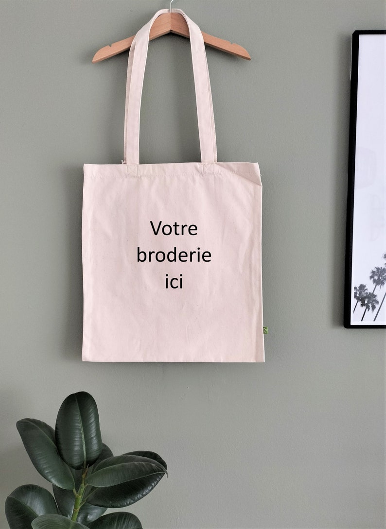 May include: A white tote bag with the text "Votre broderie ici" printed in black.