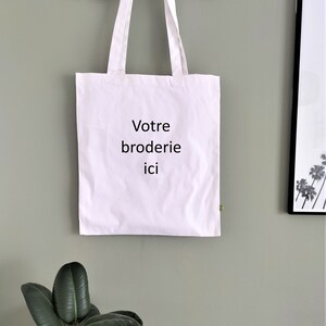 May include: White tote bag with the text "Votre broderie ici" printed in black.