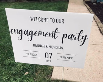 May include: White engagement party sign with black text. The sign reads "Welcome to our engagement party" in a script font, with the names "Hannah & Nicholas" below. The date is Thursday, September 7, 2023.