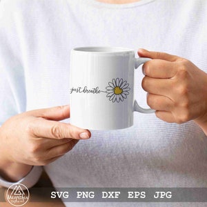 May include: White ceramic mug with a black outline of a daisy with a yellow centre and the text "just breathe" in black cursive.