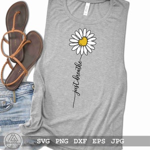 May include: A grey tank top with a white daisy with a yellow heart in the centre. The text "just breathe" is written vertically below the daisy.