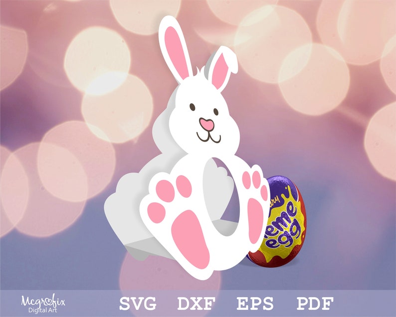 May include: White bunny shaped cardboard box with pink feet and a cut-out for an Easter egg. The box is sitting on a purple and white background. A purple and yellow chocolate egg is sitting in front of the box.