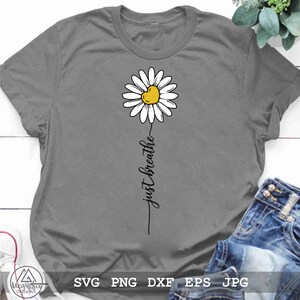 May include: A grey t-shirt with a white daisy and the text "just breathe" in black.