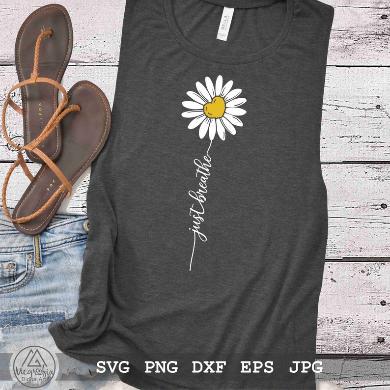 May include: A grey tank top with a white daisy with a yellow heart in the centre. The text "just breathe" is written vertically below the daisy.