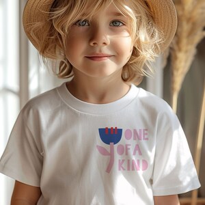 K&ouml;nnte beinhalten: Ein wei&szlig;es T-Shirt mit einer pinkfarbenen und blauen Grafik einer Blume und dem Text "ONE OF A KIND".