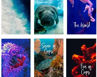 May include: Six rectangular art prints featuring underwater scenes. The prints include images of ocean waves, a manatee, seahorses, a clownfish, a sea turtle, and an octopus. Each print has a title in white script: "The Tower", "The World", "The Fool", "Seven of Cups", and "Five of Cups".