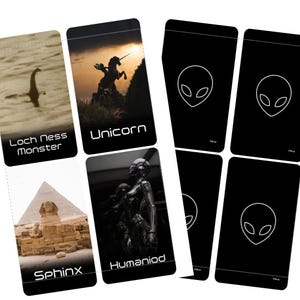 May include: A collection of black cards featuring various images and text. The cards display images of the Loch Ness Monster, a unicorn, a sphinx, and a humanoid figure. Other cards have a white alien head design.