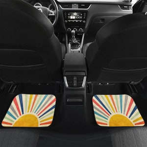 May include: Two car floor mats with a retro sunburst design. The mats are beige with colorful stripes radiating out from a yellow sun in the center.