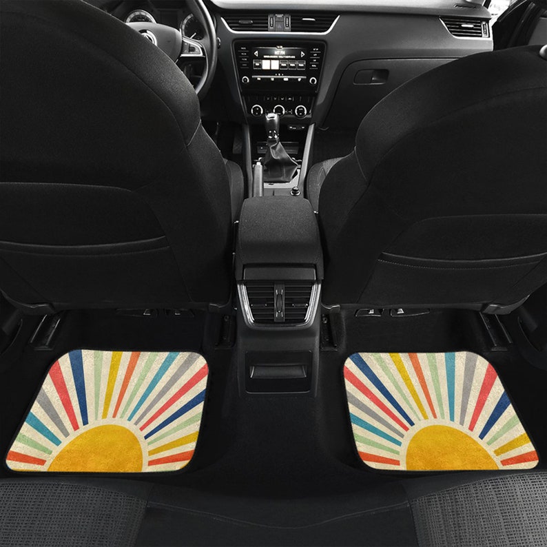 May include: Two car floor mats with a retro sunburst design. The mats are beige with colorful stripes radiating out from a yellow sun in the center.