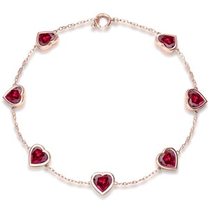 Peut inclure: Un bracelet délicat orné de sept pierres précieuses rouges en forme de cœur, serties dans une chaîne en or rose. Le bracelet est conçu avec un fermoir simple et est présenté sur un fond blanc.