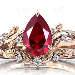 May include: A pear-shaped ruby gemstone ring set in a rose gold band with a delicate floral design and smaller diamonds.