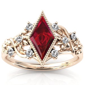 May include: A rose gold ring featuring a large, diamond-shaped, deep red gemstone as the centerpiece. The ring is adorned with smaller, round, clear gemstones and delicate floral and vine-like details.