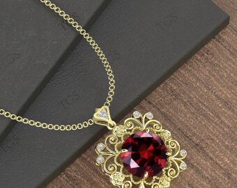 May include: A gold-colored pendant necklace featuring a large, faceted, deep red gemstone. The gemstone is set in an ornate, square-shaped frame with delicate scrollwork and small, clear accent stones. The chain is a fine, linked design.