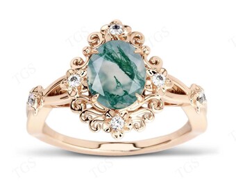 May include: A rose gold ring with a green agate oval gemstone surrounded by a floral design and smaller clear gemstones.